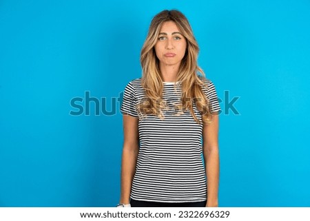 Displeased upset Young beautiful woman wearing striped t-shirt  frowns face as going to cry, being discontent and unhappy as can't achieve goals,  Disappointed model has troubles