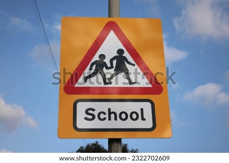 Yellow and red school sign UK blue sky in background with clouds