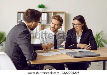 Group of business people or company employees sitting at the desk discussing work project on workplace, reaching agreement and going signing a contract. Coworkers having a meeting in office.