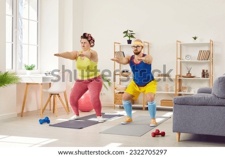 Funny plump woman doing squats with her personal trainer. Plus size woman in sportswear and curlers doing sports. Funny married couple exercising at home. Sport, slimming, dieting concept Royalty-Free Stock Photo #2322705297