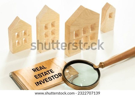 Real Estate Investor concept, Wooden blocks with the text "Investor in real estate" near a miniature housing estate. beautifully lit white background. Symbol of real estate investment bisiness