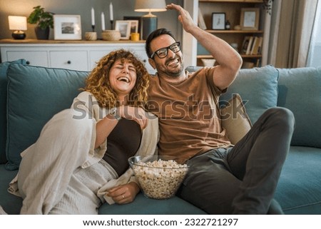 Couple man and woman caucasian husband and wife or boyfriend and girlfriend sit on the sofa bed at home watch tv movie series with bowl of popcorn happy smile bonding love family concept copy space Royalty-Free Stock Photo #2322721297