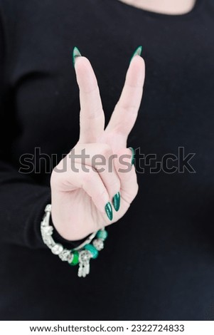 Woman's hand with long nails and emerald green nail polish