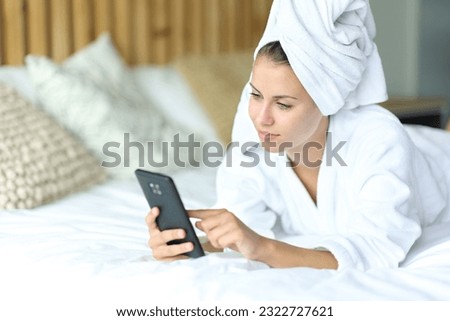 Satisfied woman using phone on bed after showering