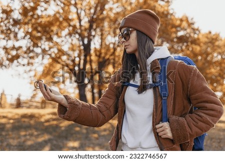 Traveling woman with backpack navigating with compass in forest  Royalty-Free Stock Photo #2322746567