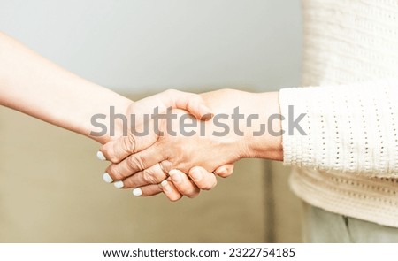 Doctor or nurse shaking hands with a senior woman at home.