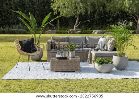 A contemporary outdoor patio space featuring a comfortable sectional couch, armchairs, decorative pillows, lush green grass Royalty-Free Stock Photo #2322756935