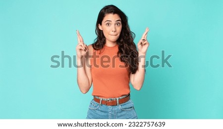 young pretty woman crossing fingers anxiously and hoping for good luck with a worried look Royalty-Free Stock Photo #2322757639