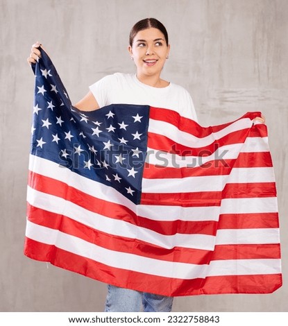 Young positive woman holding national flag of USA in her hands