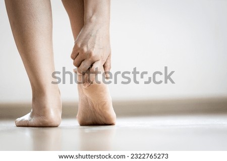 Asian woman holding heel with her hand,symptom of Plantar Fasciitis,problem of achilles tendon suffer from achilles tendinitis,pain and stiffness in muscle and ligaments of leg,feet hurt while walking