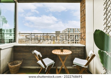 two chairs and a table in front of a window with a view of the city from it's outside