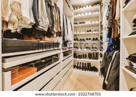 a walk - in closet with white shelvings and lots of shoes hanging on the wall behind it, Royalty-Free Stock Photo #2322768701
