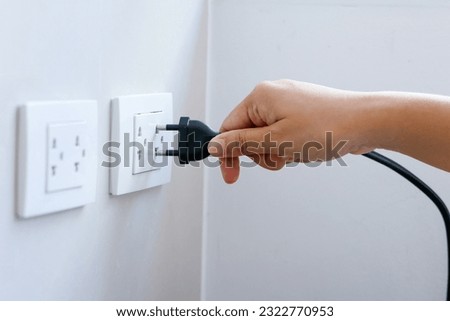 Hand holding plug to connect a power plug into a electric outlet on a wall, two electrical outlet, double power outlet, power saving concept, energy saving concept, power source concept. Royalty-Free Stock Photo #2322770953