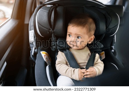 happy infant baby sitting in car seat and looking out of the window, safety chair travelling Royalty-Free Stock Photo #2322771309