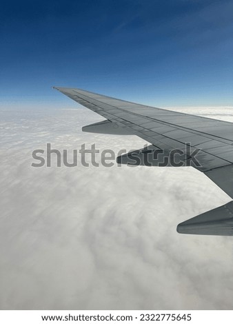 Picture of wing of the airplane which is flying over cloudy sky.