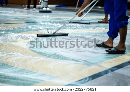 Selective focus to floor cleaners on floor with blurry the team of staff cleans using floor scrubbers, mops and rubber squeegees. Royalty-Free Stock Photo #2322775821
