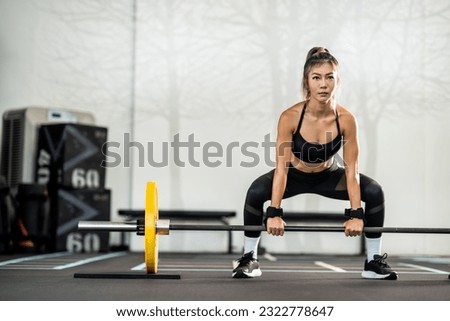 Portrait of a young Asian woman, good looking, shapely, in a black dress. She's working exercise fitness out in a world-class gym.