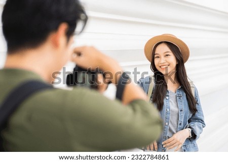 Portrait of Asian man and woman couple travelers in relationship. Boyfriend taking photo of girlfriend in front of buddhist temple on street in Bangkok, Thailand - people traveling photography concept