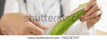 Close-up of woman nutritionist measuring size of squash or zucchini with measuring tape. Counseling about food and diet, health benefits, effect on body