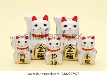 Japanese lucky cat on yellow background, Japanese word of this photography means "better fortune, blessing, economic fortune" 