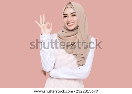 Beauty Asian young muslim girl wear hijab headscarf smiling and making OK hand sign isolated on pink background.