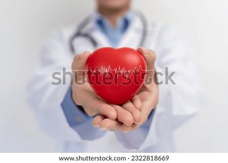 Doctor holding red heart shape in hand and modern medical network icon connected to virtual screen medical technology network concept. Medical and patient.