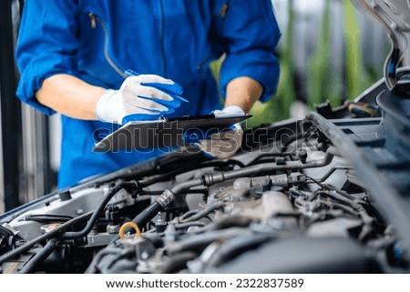 Automotive mechanic repairmen checking the system working engine of the engine room, check the mileage of the car, oil change, auto maintenance service concept. Royalty-Free Stock Photo #2322837589