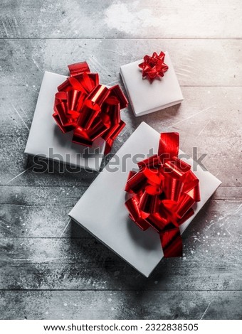 Christmas boxes with bows of different sizes. On white rustic background