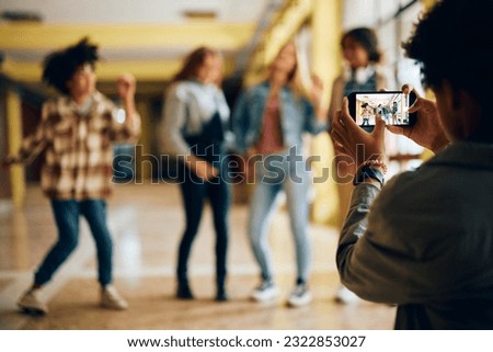 Close up of high school student taking picture of his friends with smart phone.