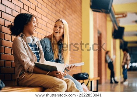 Cheerful teenage girl having fun while studying in high school hallway. Royalty-Free Stock Photo #2322853041