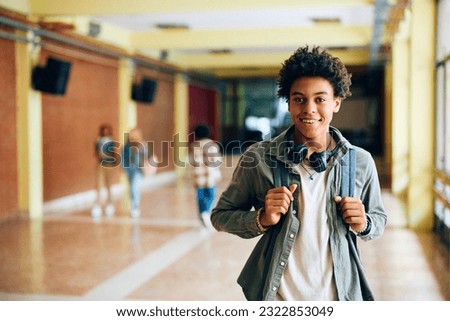 Happy African American high school student standing in hallway and looking at camera. Royalty-Free Stock Photo #2322853049