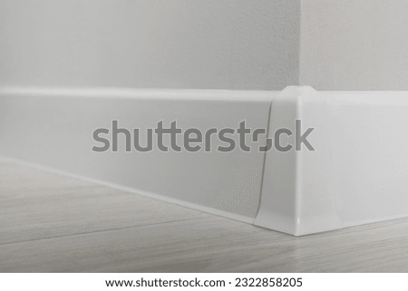 White plinth with connector on laminated floor near wall indoors, closeup Royalty-Free Stock Photo #2322858205