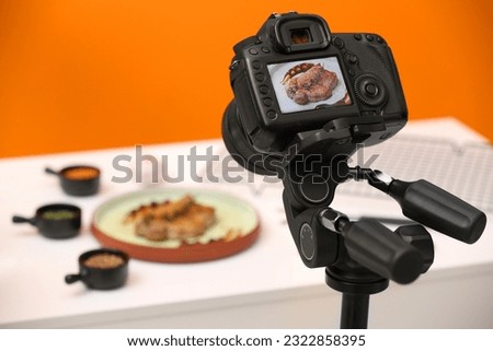 Professional camera with picture of meat medallion on display in studio, space for text. Food stylist