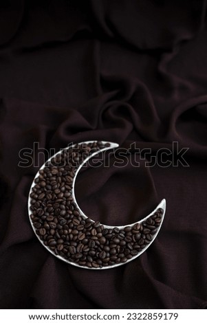 coffee beans in a crescent moon shape plate isolated on brown colour background with copy space