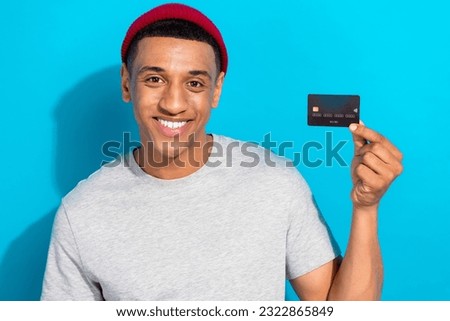 Photo of friendly positive person toothy smile hand hold demonstrate plastic debit card isolated on blue color background