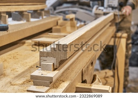 Carpenter milling wooden handrail with router manual milling machine in workshop close up. Handyman processes timber piece with electric instrument Royalty-Free Stock Photo #2322869089