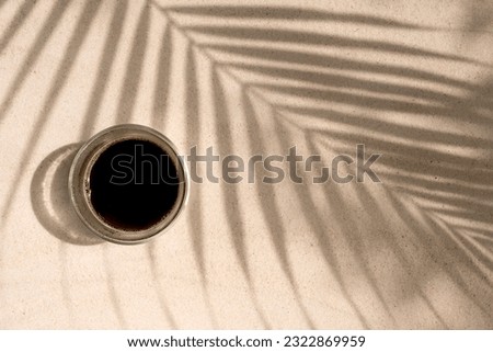 Cup coffee on palm shade at the beach. Royalty-Free Stock Photo #2322869959