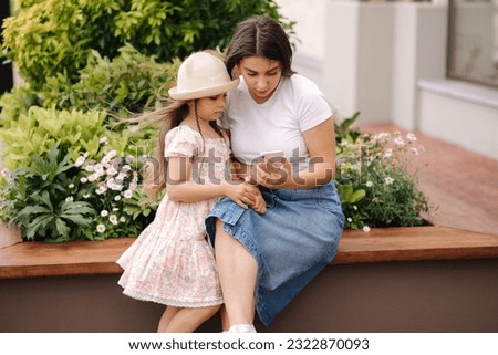 Mom and daughter looking pictures on phone. Beautiful girls using phone outdoor