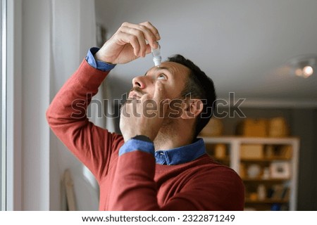 Close-up of young man applying eye drops to treat dry eye and irritation at home Royalty-Free Stock Photo #2322871249