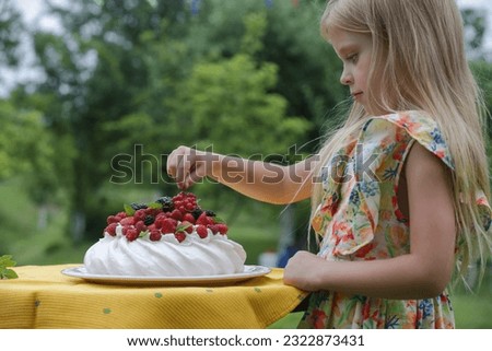 Adorable little girl in floral summer dress eating Pavlova cake Royalty-Free Stock Photo #2322873431