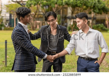 A young asian man successfully gets two former friends and now enemies to shake hands, reconcile and call a truce. A great friend acting as a mediator to patch things up. Royalty-Free Stock Photo #2322885899