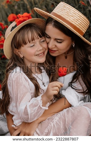 Beautiful young woman with girl in field with poppies, mother and daughter in white dresses and straw hats in evening at sunset, Summer countryside nature flowers, family relaxing, Rural simple life