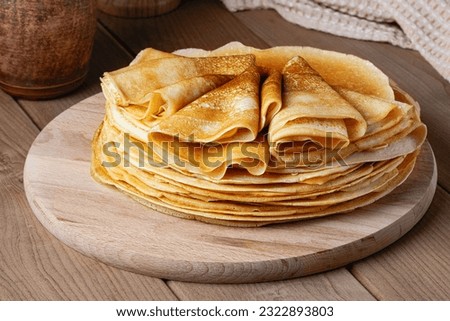 Thin pancakes on a wood plate. Homemade crepes, tasty food. Staple of yeast pancakes, traditional for Russian pancake week (Shrove tide). Thin pancake with crispy crust Royalty-Free Stock Photo #2322893803
