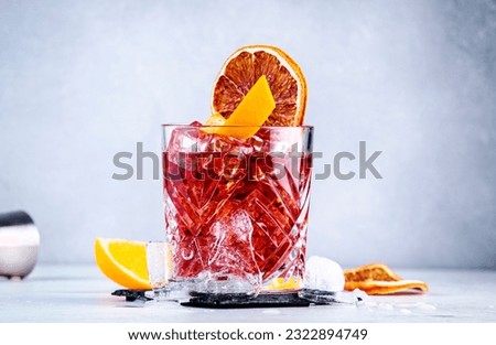 Negroni alcoholic cocktail drink with dry gin, red vermouth and red bitter, orange slice and ice cubes. Gray background, bar tools, copy space Royalty-Free Stock Photo #2322894749