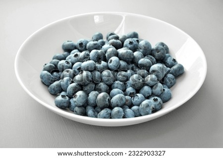 blueberries in a transparent plate on a gray background
