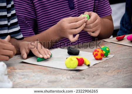 Asian boys sitting together and learning in plasticine molding by using lumps of plasticine on table, selective focus on left boy, concept for free time and hobby activity of children over the world.