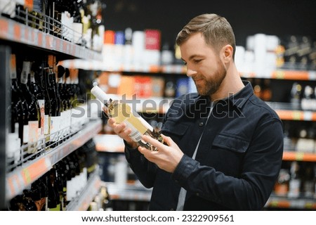 Man in a supermarket choosing a wine. Royalty-Free Stock Photo #2322909561