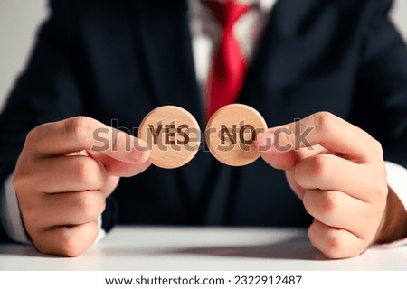Businessman holding wooden piece YES or NO for decision making idea choice by two hands on white table background. Business commerce investment selection choosing and option.