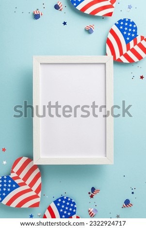 Red, White, and Blue cheers. Overhead vertical perspective of emblematic decorations: American flag-inspired hearts, confetti on pastel blue backdrop with empty photo frame for text or picture