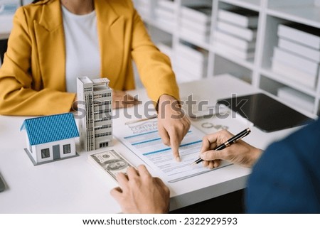 Real estate broker agent presenting and consult to customer to decision making sign insurance form agreement, home model, concerning mortgage loan offer.